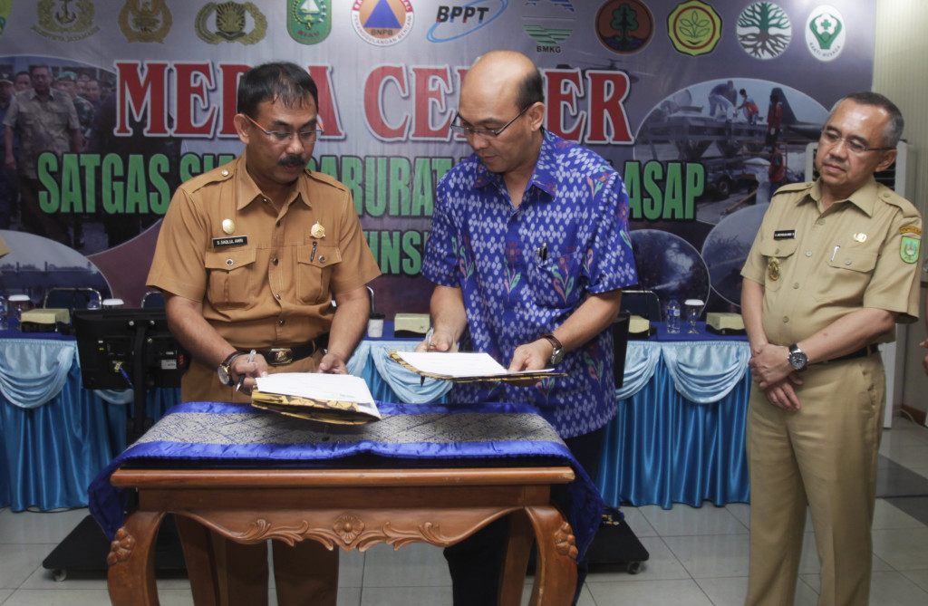 Riau Andalan Pulp and Paper (RAPP) Director Mulia Nauli (center), signs a Memorandum of Understanding with the Riau Regional Disaster Mitigation Agency at Roesmin Nurjadin military airbase in Pekanbaru, Riau, on June 26. The signing ceremony was witnessed by Riau Deputy Governor Arsyad Juliandi Rachman (right) and Said Saqlul Amri, head of the Riau Province Disaster Mitigation Agency (left). (GA Photo/A.A. Kresna) 